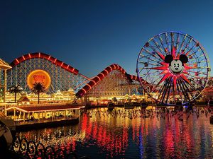 Disneyland, ferris wheel and rollercoaster lit up at dusk