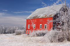 A red barn sits in a snowy field.
