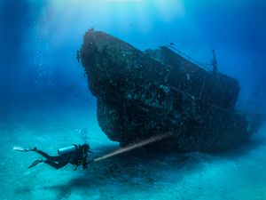 Full Length Of Woman Diving Underwater By Shipwreck