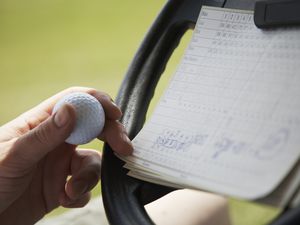 Golf scorecard attached to the steering wheel of a cart.