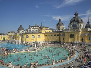 A busy outdoor thermal bath with classic Hungarian architecture