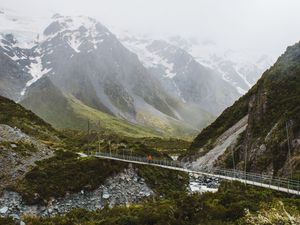 A person in a red jacket crossing a hanging bridge on the Hooker Valley Trail