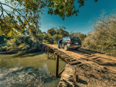Tourist with car breakdown on a large, rickety wooden bridge in the middle of the wilderness of Paraguay.