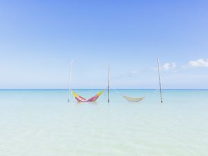 Two hammocks in the crystal clear turqoise water at a beach on the Island of Holbox, Mexico