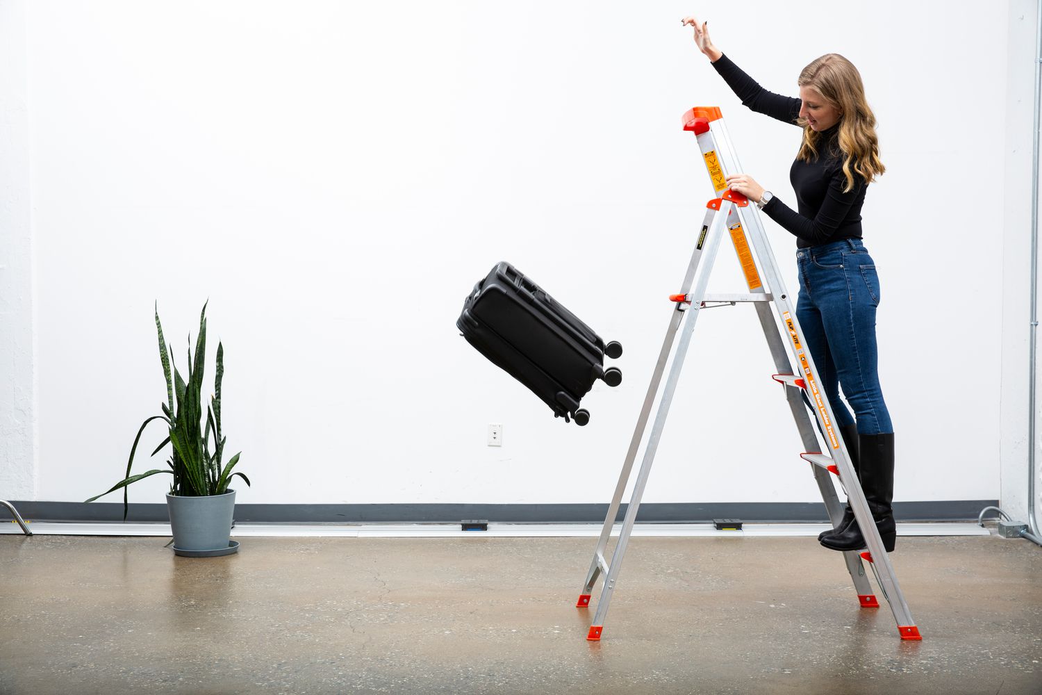 pushing a suitcase off a ladder to test durability
