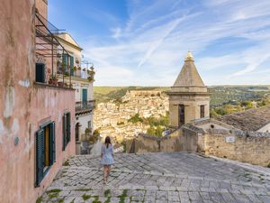 Woman climbing the stairs of Santa Maria delle scale church, Ragusa Ibla in the background, Ragusa, Sicily, Italy, Europe