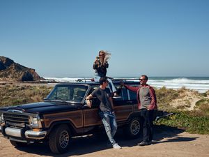 Woman taking photo from roof of car on the coast of Portugal